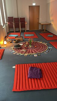 Das Foto zeigt einen Raum, der mit Matten ausgelegt ist. In der Mitte ist eine Entspannungsinsel dekoriert.